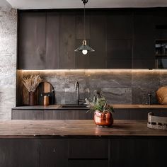 a kitchen with dark wood cabinets and counter tops is lit by lights above the sink