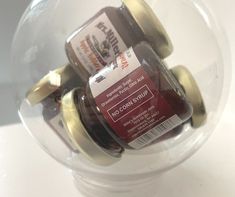 two jars of peanut butter in a clear glass container on a white surface with gold rims