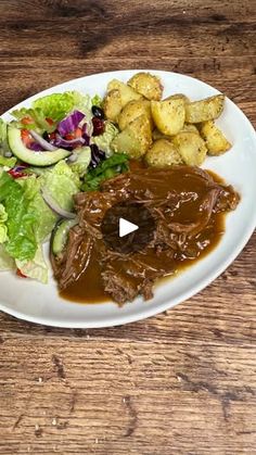 a white plate topped with meat and vegetables next to gravy on top of a wooden table