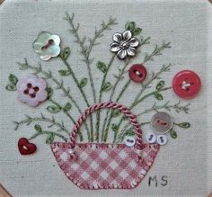 a close up of a embroidery on a piece of cloth with buttons and flowers in it