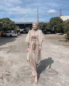 a woman wearing a hijab and standing in the middle of a parking lot