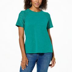 a woman standing with her hands in her pockets and wearing a green t - shirt