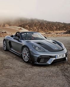 a grey sports car parked on top of a dirt field