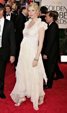 a woman in a white dress standing on a red carpet