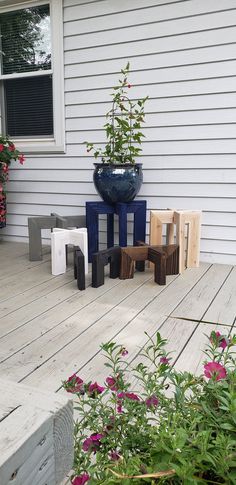 some chairs and tables on a wooden deck near a flower pot with flowers in it