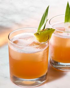 two glasses filled with drinks sitting on top of a table