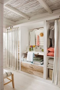 a bathroom with white walls and wood flooring next to a window covered in curtains