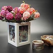 a vase filled with pink and white flowers next to an empty cup on a table