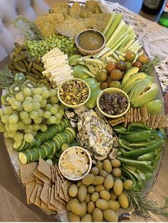 a platter filled with grapes, olives, crackers and other food items