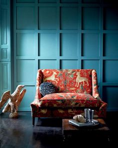 a living room filled with furniture and walls covered in blue paneled wood panels next to a fire place