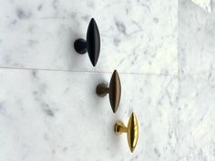 three brass and black knobs on a marble wall