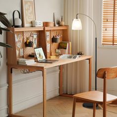 a wooden desk sitting next to a chair in a room with white walls and wood flooring