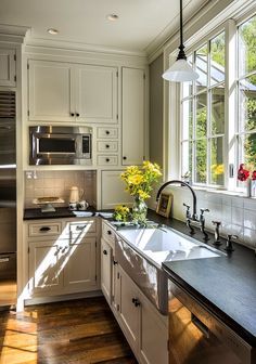 a large kitchen with white cabinets and stainless steel appliances in the center, along with wooden floors