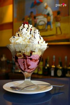 an ice cream sundae with chocolate sauce and whipped cream in a glass dish on a table