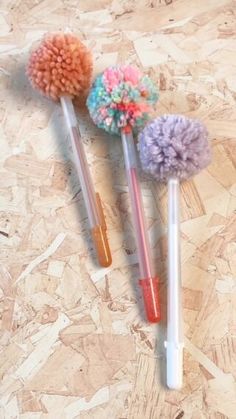 three different colored pom - poms sitting on top of a wooden floor next to each other