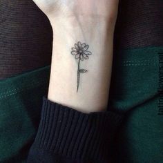 a woman's wrist tattoo with a flower on the left side of her arm