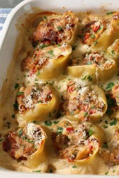 a casserole dish filled with shells covered in cheese and meat sauce, garnished with parsley