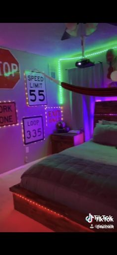 a bed room with a neatly made bed and neon signs on the wall above it