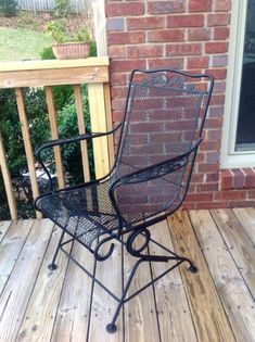 a chair sitting on top of a wooden deck next to a brick wall and window