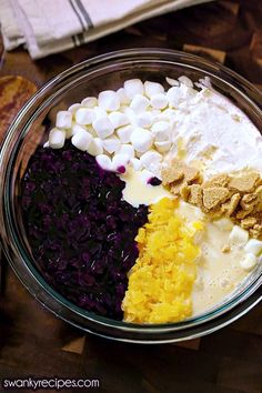 a bowl filled with different types of food on top of a wooden table next to bread