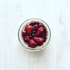 a bowl filled with oatmeal and strawberries on top of a wooden table