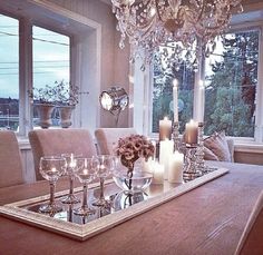 a dining room table with candles and wine glasses on it, in front of a large window