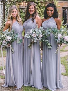 three bridesmaids in grey dresses holding bouquets with greenery and flowers on them