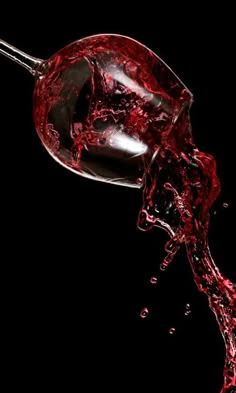 red wine being poured into a glass on a black background with water splashing around it