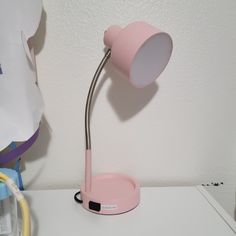 a pink desk lamp sitting on top of a white table