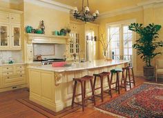 a large kitchen with an island in the middle and two stools at the end