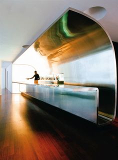 a person standing at a counter in a room with wood floors and white walls on the wall