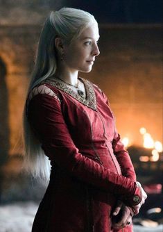 the white haired woman is dressed in red and wearing a long, braided ponytail