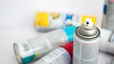 several cans of spray paint sitting next to each other on a white counter top,