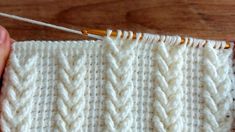 someone is stitching the end of a white knitted blanket