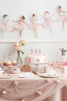 a table topped with cake and cupcakes covered in pink frosting