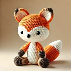 an orange and white knitted fox sitting on top of a table