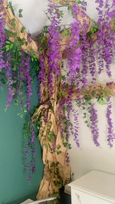 purple flowers are growing up the side of a wall in a room with green walls