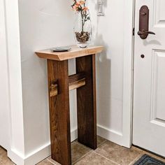 a vase with flowers sitting on top of a wooden table in front of a door