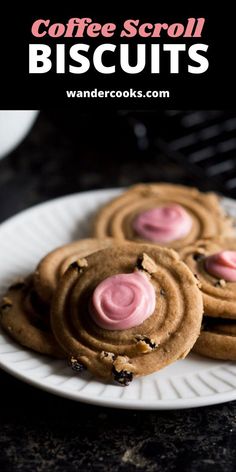 three cookies with pink icing are on a white plate next to some other cookies