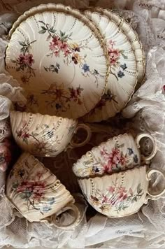 an assortment of porcelain dishes and cups on lace