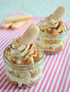 two jars filled with desserts sitting on top of a red and white table cloth