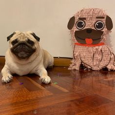 a pug dog laying on the floor next to a paper cut out of a dog