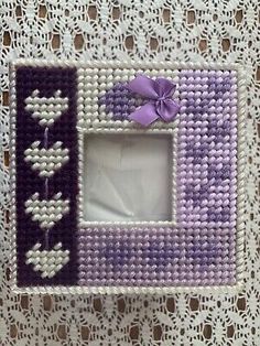 a purple and white photo frame with a bow on the top is sitting on a lace doily