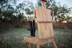 an easel with several different types of paint on it in the middle of a field