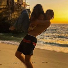 a man and woman are running on the beach at sunset, with an ocean in the background