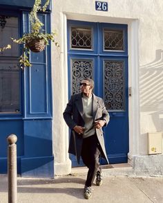 a man walking down the street in front of a blue door