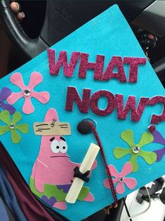 a blue graduation cap with the words what now? written on it and a cartoon character holding a microphone