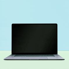 an open laptop computer sitting on top of a white table next to a blue wall