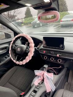 the interior of a car decorated with pink and grey accessories, including a steering wheel