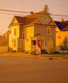 a yellow two story house sitting on the corner of a street